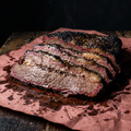 Sliced Texas smoked brisket with black pepper bark, fat cap and smoke ring on pink butcher paper